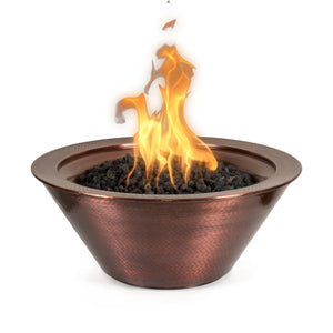 Hand-hammered copper Cazo fire bowl with a warm, glowing flame rising from a bed of black lava rock. This round gas fire feature showcases artisan craftsmanship and timeless elegance—perfect for upscale outdoor living spaces.