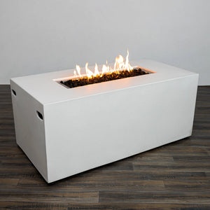 A three-quarter angle of the Starfire Designs Beton 55" White Rectangle Hidden Propane Tank Gas Fire Pit showcasing its sleek edges and generous flame area. The rectangular fire pit features recessed side handles for portability and a white finish for a contemporary look. The fire pit emits a warm glow over decorative lava rocks.