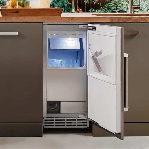 An outdoor ice maker is open in an outdoor BBQ kitchen