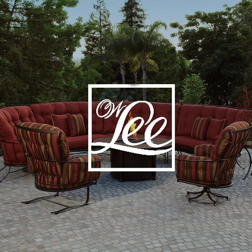 OW Lee luxury outdoor furniture featuring a curved sectional and swivel chairs with vibrant red and striped cushions, set on a cobblestone patio surrounded by lush greenery and palm trees for stylish outdoor living.