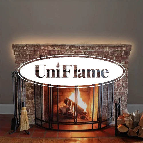 UniFlame traditional brick fireplace with a wrought iron fire screen, cozy flames burning logs, and matching fireplace tool set, perfect for enhancing warmth and style in any classic living room setting.