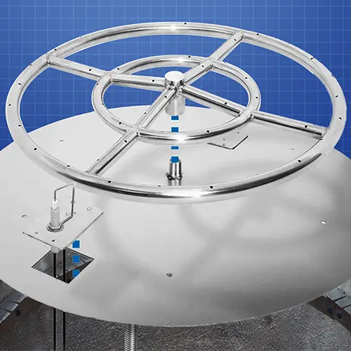 A gas fire pit ring is being installed into a burner pan with a push button ignitor and placed into a DIY fire pit setup