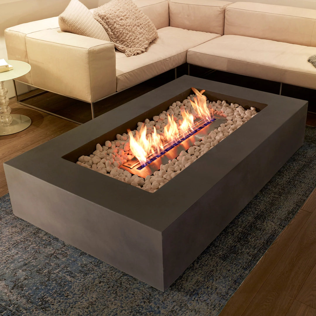 A gray EcoSmart Fire ethanol fire pit is burning inside a living room next to some comfortable furniture.