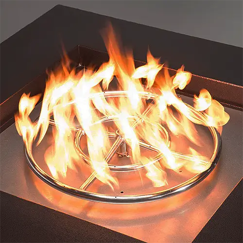 a stainless steel fire pit burner ring is set ablaze in a steel fire pit