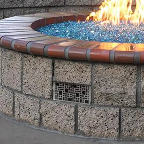 a closeup of a fire pit vent in a DIY outdoor fire pit laid with fire glass and ignited