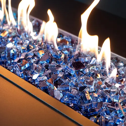 a closeup photo of half inch cobalt blue fire glass is set ablaze in a fire pit
