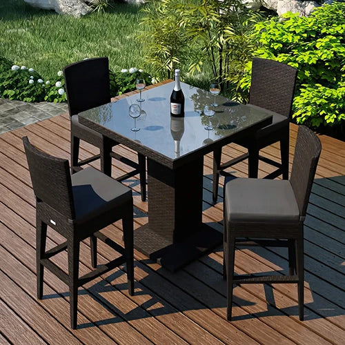A high-top outdoor bar set featuring a sleek black rattan table with a glass top and four matching wicker bar stools with gray cushions.