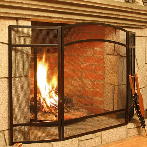 A fireplace screen and blower are sitting in front of a wood burning fireplace