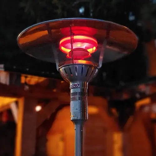 an outdoor natural gas heater is heating an outdoor patio at night as it glows red with heat
