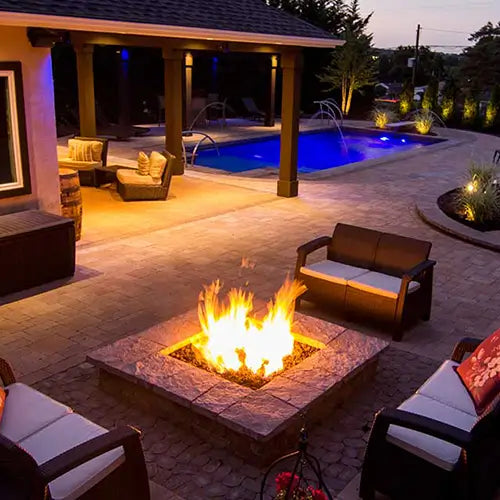 an array of outdoor items are displayed at golden afternoon hour such as a DIY fire pit and patio set by the pool