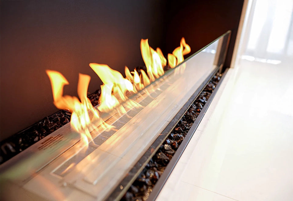 Linear gas fireplace with 1/2-inch broken fire glass and vibrant flames, featuring a sleek modern design with black fire media and a glass safety barrier.