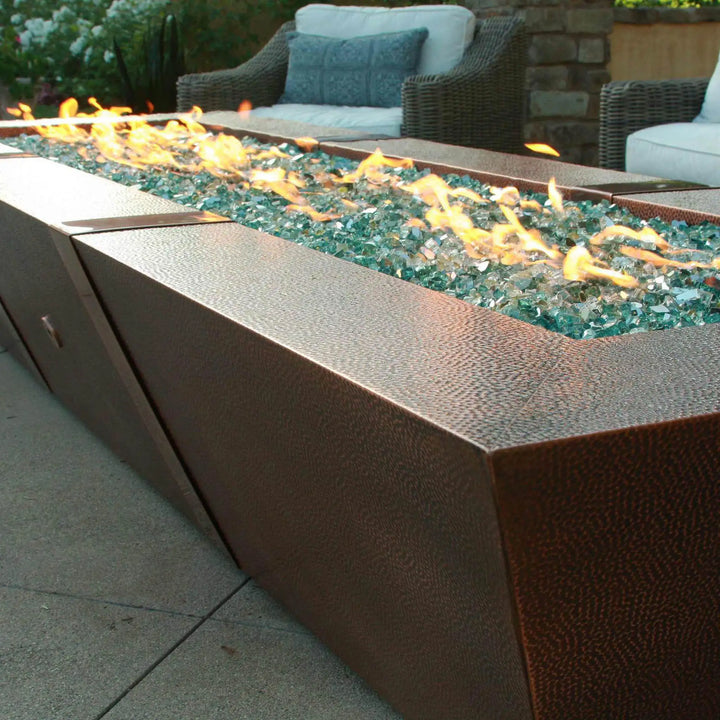 Starfire Designs 10ft Copper Spartan Gas Fire Pit on a sunny patio, featuring a sleek hammered copper design and long, rectangular shape for outdoor spaces