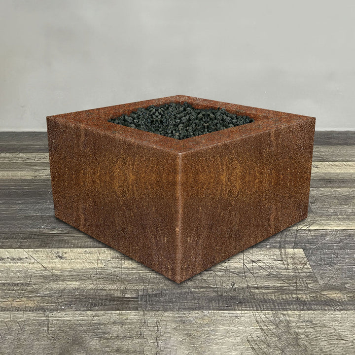 A side view of the 36" Square Gravity Corten Steel Fire Pit - Propane Gas Hardline - 110V CSA Hi/Lo Electronic Ignition System w/Bluetooth & Handheld Remote by Starfire Designs - perfect for outdoor patio spaces. Natural gas or propane compatible, enhancing warmth and ambiance. Lava rocks included for added aesthetic.
