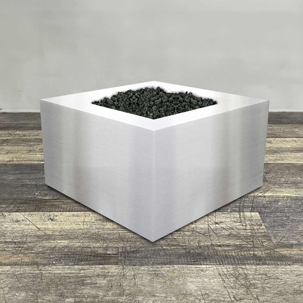 A side view of the 36" Square Gravity Stainless Steel Fire Pit by Starfire Designs - perfect for outdoor patio spaces. Natural gas or propane compatible, enhancing warmth and ambiance. Lava rocks included for added aesthetic.