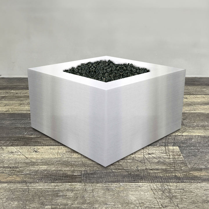 A side view of the 36" Square Gravity Stainless Steel Fire Pit by Starfire Designs - perfect for outdoor patio spaces. Natural gas or propane compatible, enhancing warmth and ambiance. Lava rocks included for added aesthetic.