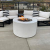 Modern outdoor patio setup featuring a 42-inch round white concrete fire pit with hidden propane tank by Starfire Designs, surrounded by cushioned sectional seating and black metal frames / perfect for cozy evenings and backyard gatherings.