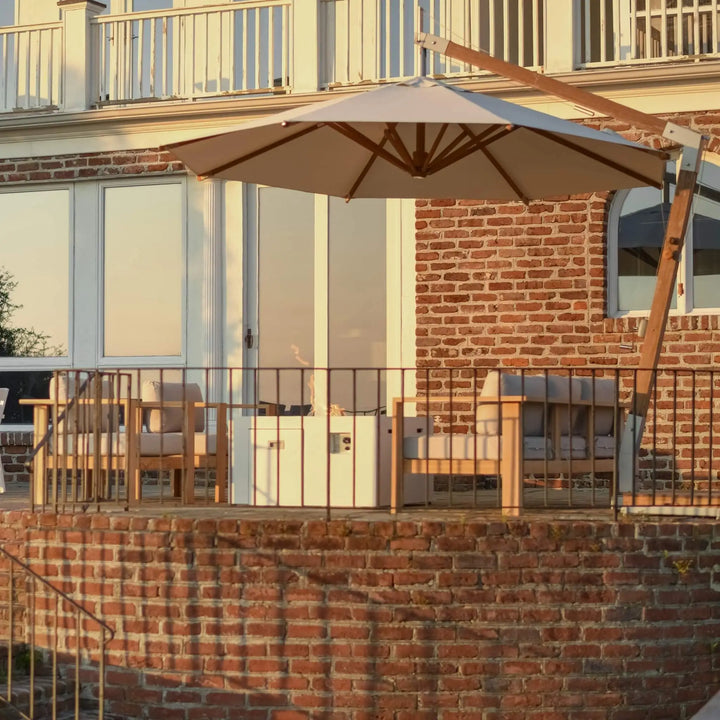 Cozy elevated brick patio featuring the 42-Inch Square Beton Concrete GFRC Gas Fire Pit in White by Starfire Designs, seamlessly integrated with plush cushioned seating and a cantilever umbrella / captured at golden hour, perfect for stylish and relaxing outdoor moments.