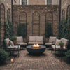 In a narrow brick courtyard bordered by tall brick walls with climbing vines and arched trellises, cushioned metal lounge chairs form a semicircle around a dark round fire bowl set directly on the herringbone pavers, its compact flame dancing above stones while string lights and candles add soft illumination, creating a patio fire pit vignette that feels like a cozy backyard fire pit designed for intimate outdoor entertaining.