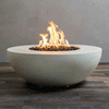 A smooth white fire bowl shaped like a wide, shallow half sphere sits on a striped wood-look floor against a plain gray wall, its recessed center filled with dark lava rocks while tall yellow flames from the gas fire pit rise and fold back on themselves, clearly outlining the round concrete fire pit’s low profile, broad rim, and soft matte texture as it appears to hover just above the ground.