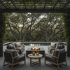 A modern fire pit with a square graphite profile sits under a vine-covered pergola, framed by large oak trees and a swimming pool. The symmetrical seating arrangement highlights the fire feature as the focal point of a lush backyard oasis. The steady flames of the patio fire pit enhance the natural serenity of the garden estate.