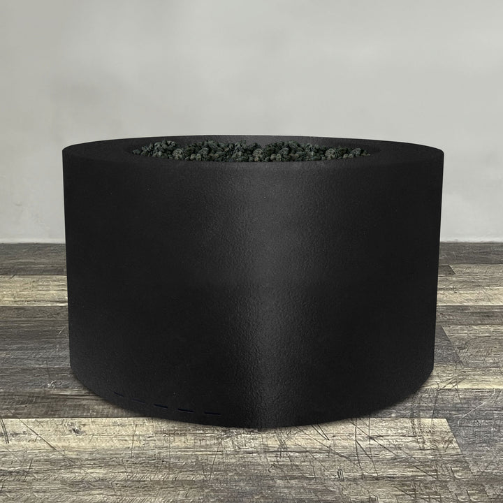 A side view of the 45" Round Gravity Powder Coated Steel Fire Pit - Natural Gas - 110V CSA On/Off Electronic Ignition System - Black Hammertone by Starfire Designs - perfect for outdoor patio spaces. Natural gas or propane compatible, enhancing warmth and ambiance. Lava rocks included for added aesthetic.