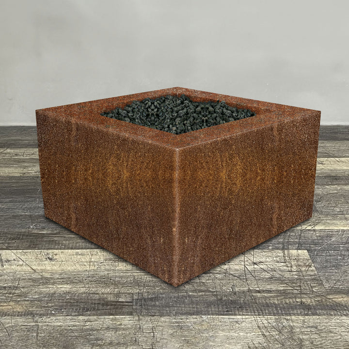 A side view of the 45" Square Gravity Corten Steel Fire Pit by Starfire Designs - perfect for outdoor patio spaces. Natural gas or propane compatible, enhancing warmth and ambiance. Lava rocks included for added aesthetic.