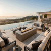 A brown luxury fire pit sits on a tiled terrace next to an infinity pool, overlooking the ocean at sunset. Surrounded by cushioned sofas, the modern fire pit anchors the outdoor lounge area. The clean-burning flames illustrate the benefits of a smokeless fire pit, providing warmth and style for this sophisticated patio fire pit arrangement.
