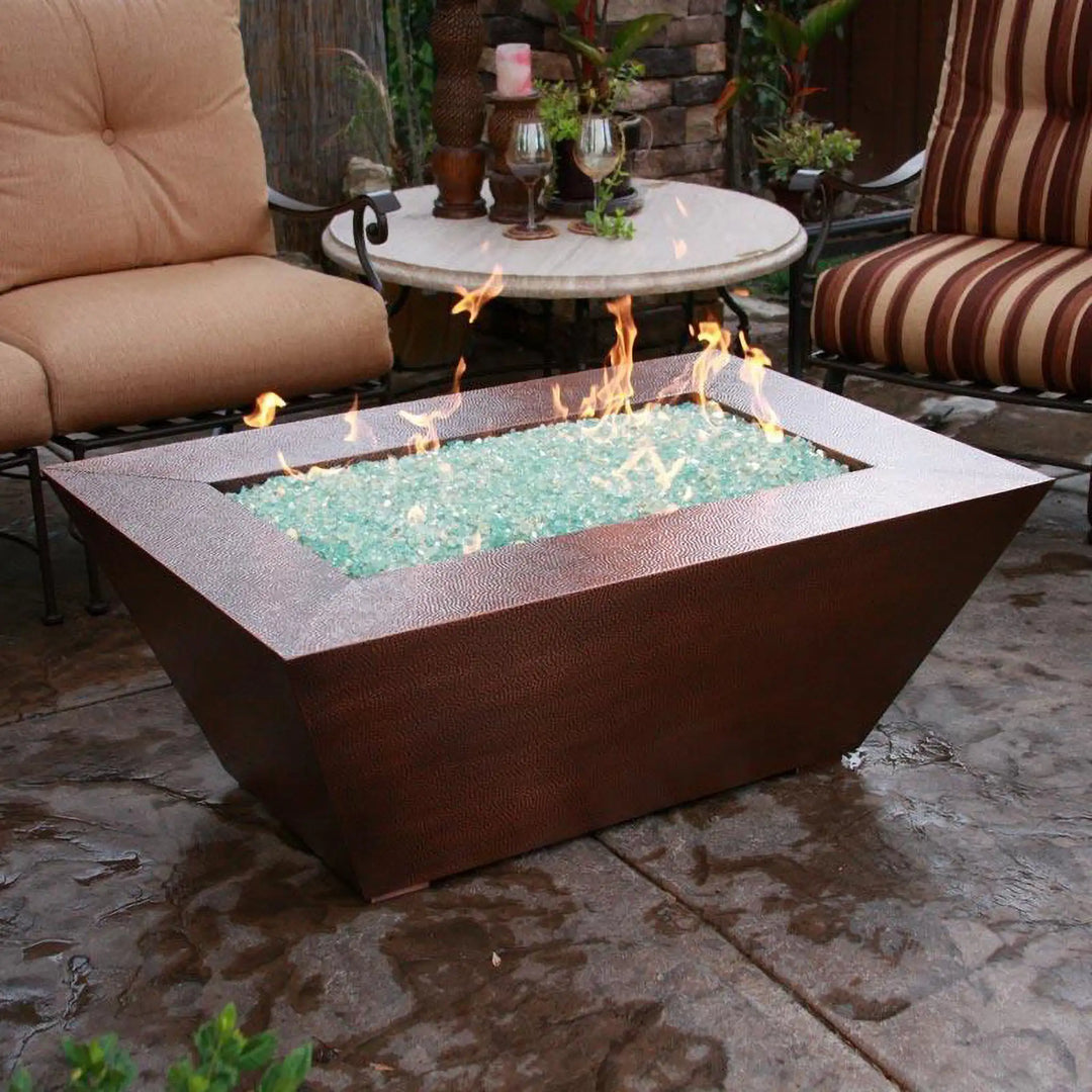 Close-up of the 60" x 32" Copper Canyon gas fire pit by Starfire Designs, with a hammered copper finish and vibrant flames, ideal for outdoor patios