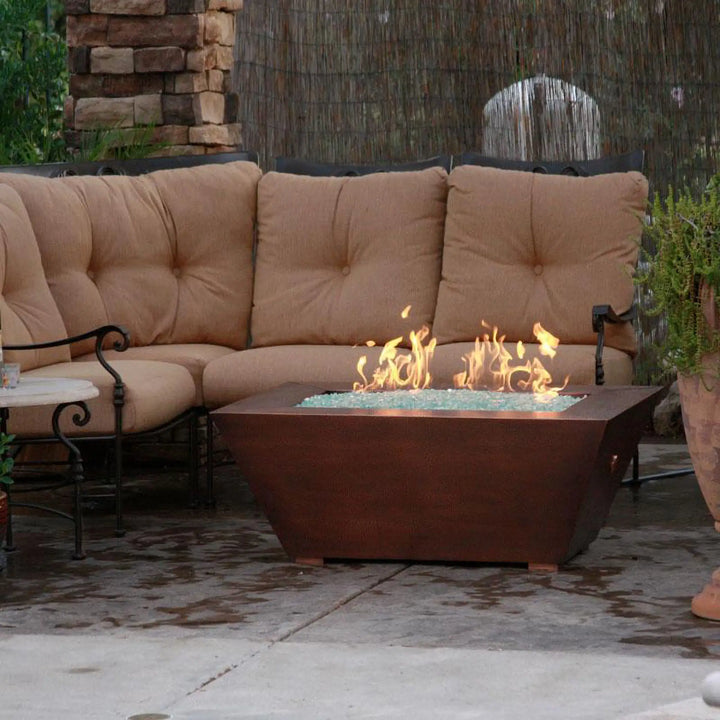 60" x 32" Copper Canyon gas fire pit by Starfire Designs, enhancing an outdoor patio with a cozy seating area, perfect for creating a warm and inviting ambiance