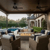 A covered poolside veranda features a gray fire table positioned between large wicker sofas. The setting overlooks a swimming pool and lush hedges, creating a private backyard oasis. The steady flames provide warmth and ambiance, making it the perfect family gathering fire pit area within a sheltered outdoor living space.