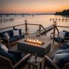 A brown rectangular concrete fire pit glows at the center of a lakeside deck framed by wood railings and lanterns, its linear flame rising above dark stones while navy cushioned chairs and a sofa circle the hearth, a long dock and sailboats floating on still water beyond, presenting an outdoor fire pit that serves as a modern rectangular fire pit and welcoming backyard oasis for sunset outdoor entertaining by the shore.