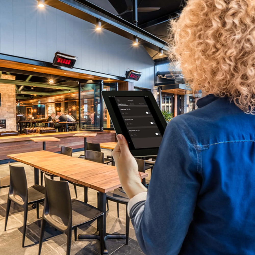 Restaurant patio setting with Bromic outdoor heaters controlled through the Affinity app, demonstrating how users can easily adjust heating zones via a tablet or smart device.