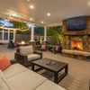 Covered patio featuring Bromic Tungsten Electric Smart-Heat black heaters mounted to the ceiling, providing cozy warmth for a stylish outdoor living area with a stone fireplace and TV.