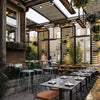 Rustic restaurant patio featuring Bromic Tungsten Electric Smart-Heat heaters mounted under a wood pergola, keeping guests comfortable in a cozy, plant-filled outdoor dining space.