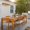 Modern residential patio with Bromic Tungsten Electric Smart-Heat heater mounted above a teak outdoor dining set, providing radiant warmth for family gatherings and outdoor meals.