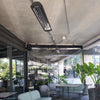 Modern café in Chile with ceiling-mounted Bromic Tungsten Electric Smart-Heat heaters, providing radiant warmth in a semi-enclosed patio surrounded by greenery and glass walls.