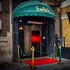 Elegant nightclub entrance in London with a Bromic Tungsten Electric Smart-Heat heater mounted above the door, warming the red-carpet entryway beneath a green awning.