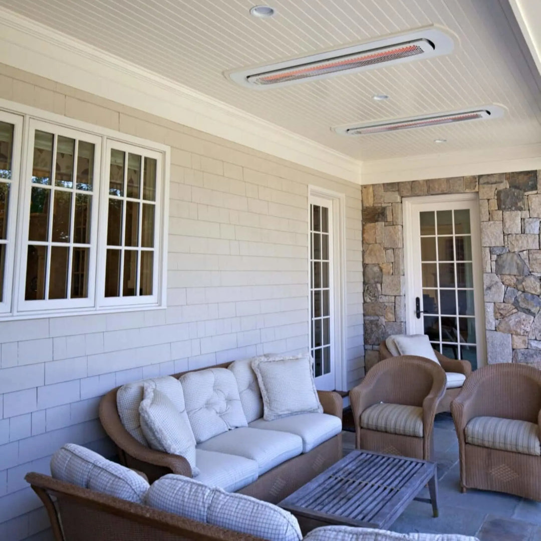Outdoor seating area with wicker furniture under a beaded ceiling, featuring Bromic Tungsten Smart-Heat heaters installed in white recessed kits for a clean, integrated look.