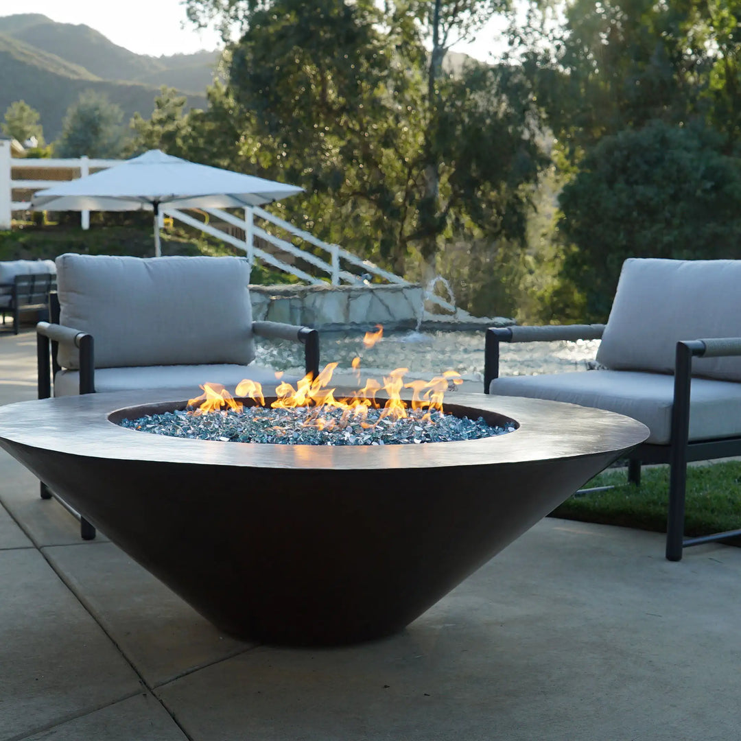 Cono Moreno 48-inch Round Copper Fire Pit by the poolside during an evening gathering, creating a warm and inviting ambiance