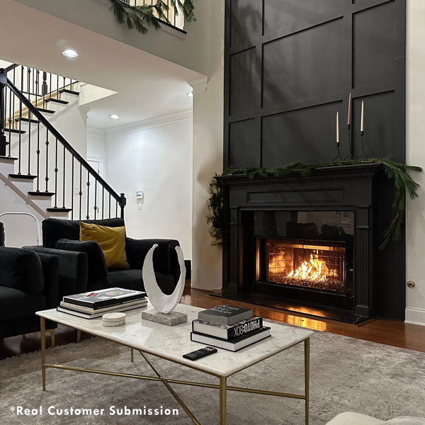 Elegant living room with a black paneled fireplace, marble coffee table, and modern decor, showcasing a cozy and stylish space perfect for relaxation