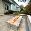 Cozy backyard patio featuring a stone gas fire pit with bright, linear flames powered by the HPC Fire Inspired Linear Flat Torpedo T-Burner—perfect for cool evenings and gatherings.