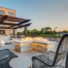 Upscale commercial rooftop lounge with an L-shaped stone fire feature producing tall, vibrant flames from the HPC Fire Inspired Linear Flat Torpedo T-Burner, creating a warm evening ambiance.