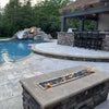 Luxurious backyard pool area featuring a long stone fire pit illuminated by the HPC Fire Inspired Torpedo T-Burner, creating a warm and inviting atmosphere for outdoor entertaining.