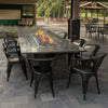 Rectangular granite fire table featuring an HPC Fire Inspired stainless steel burner with vibrant flames, surrounded by black metal chairs in a covered outdoor patio dining space.