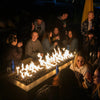 Group of friends gathered around a rectangular fire table with vivid flames and smooth stones, enjoying a lively evening outdoors filled with warmth and laughter.