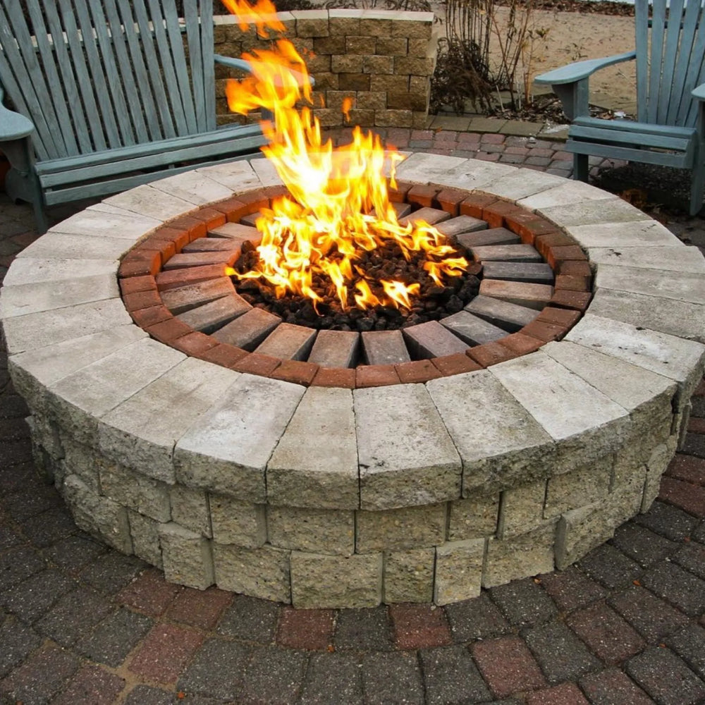 Torpedo-style Penta burner in action, installed inside a round backyard stone fire pit, delivering tall, vibrant flames surrounded by lava rocks / perfect for cozy outdoor gatherings.