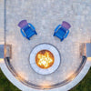 Top-down view of a round stone fire pit ignited by an HPC Penta burner, flanked by two purple chairs on a spacious patio—delivering radiant warmth and an inviting outdoor vibe.