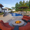 Built-in round fire pit powered by a Penta burner, situated near a luxury backyard pool with cascading waterfalls, curved seating, and elegant paver hardscape for the ultimate outdoor retreat.