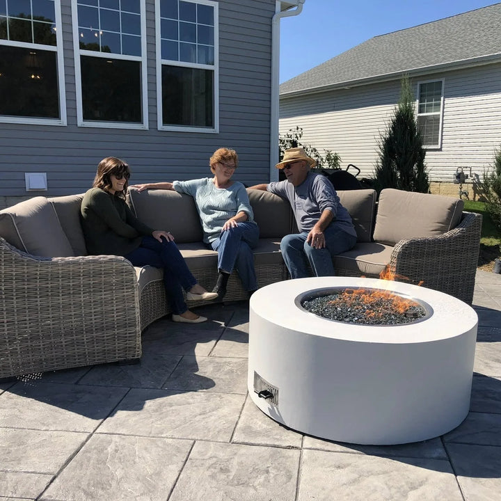 A contemporary white round fire pit with glass media is the center of a friendly backyard conversation, illustrating the perfect fire feature for patios and gatherings.