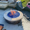 Outdoor fire pit with stacked stone base and sparkling blue fire glass, burning clean flames powered by a Penta burner drop-in system from HPC Fire.